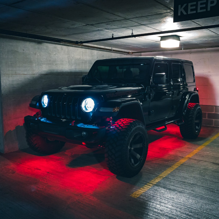 Jeep in a parking garage with red rock lights turned on.