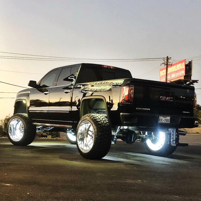 Rear three quarters view of a black GMC Sierra with white wheel rings installed.