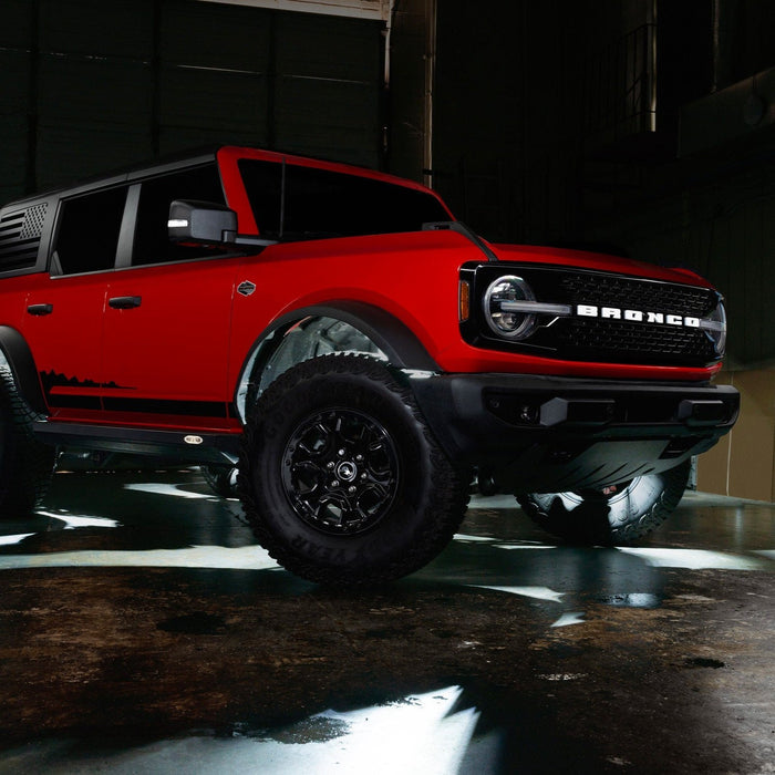 Red Ford Bronco in a garage with white rock lights turned on.