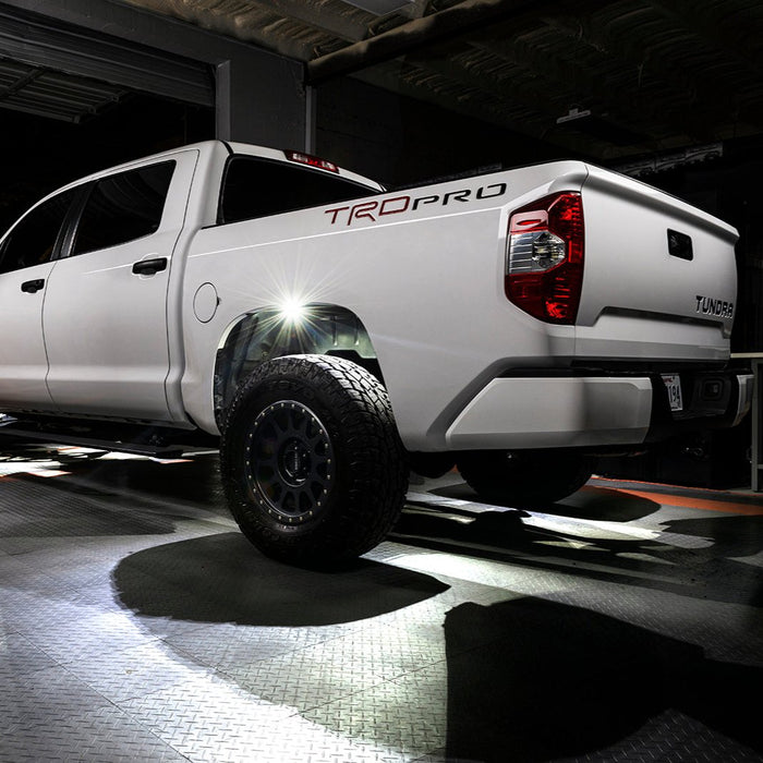 White truck with white rock lights shining in wheel well.