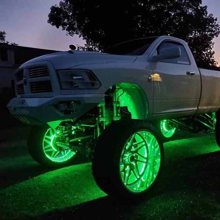 Front three quarters view of a white truck with green LED wheel rings installed.