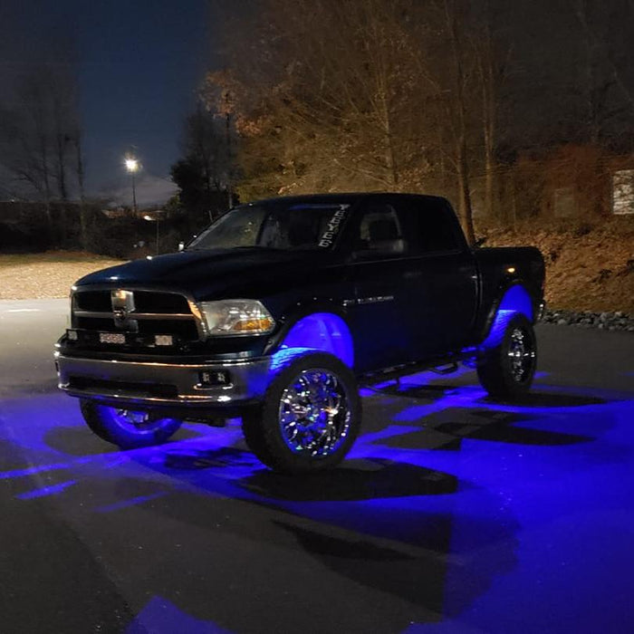 Black truck in a parking lot with blue rock lights glowing.