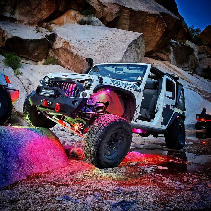 A white Jeep on a trail, with multiple aftermarket products installed, including Underbody Wheel Well Rock Lights.