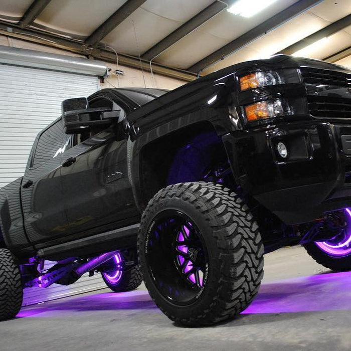 Low aggressive shot of a black Chevrolet truck with purple LED wheel rings installed.