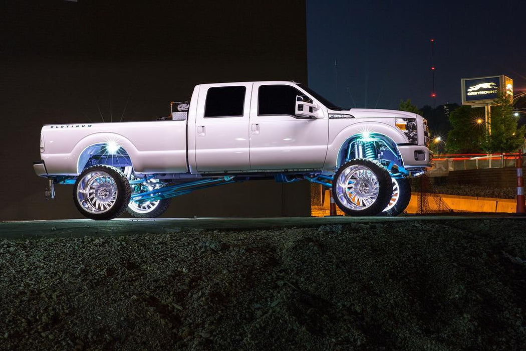 White Ford Superduty with white wheel rings and rock lights installed.