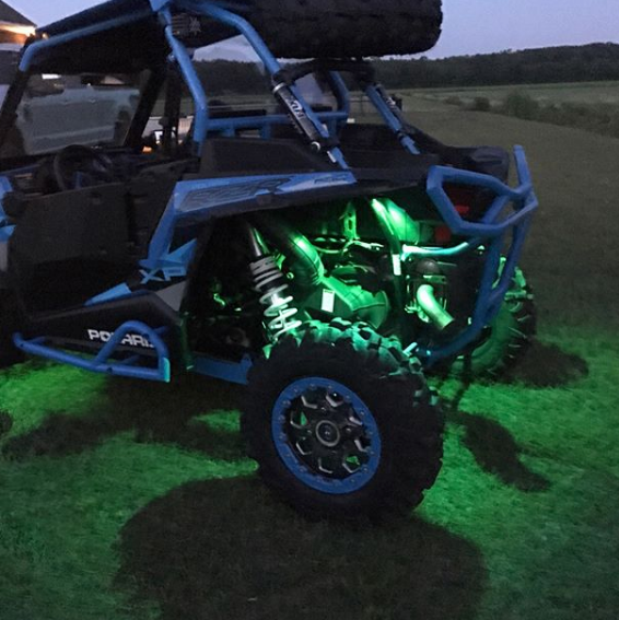 Polaris RZR outside with green rock lights installed.