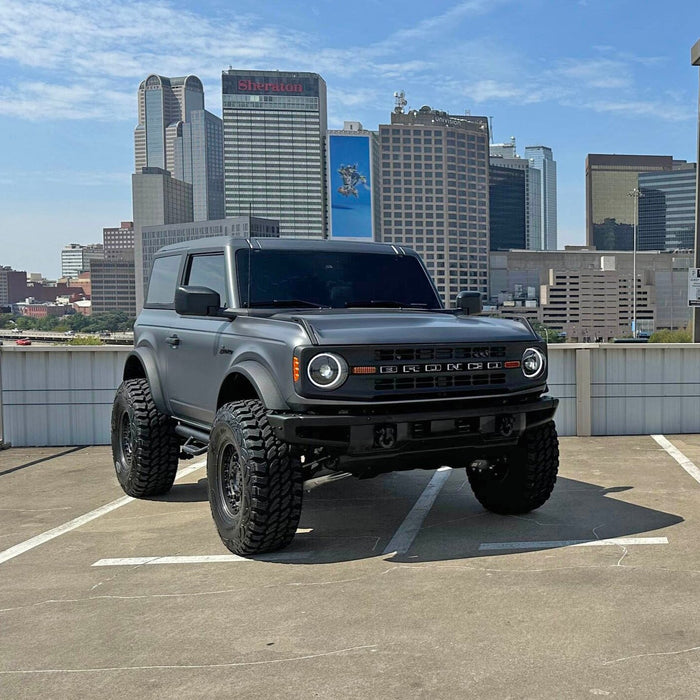 Two Ford Broncos on a rooftop parking lot, both equipped with Oculus Headlights.