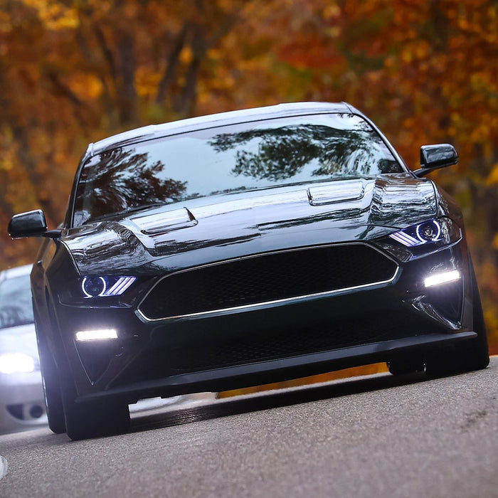 Black Mustang driving on a with white LED headlights.