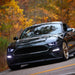 Three quarters view of a black Ford Mustang with white LED headlights.