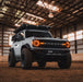 White Ford Bronco in a large barn, with amber Oculus Headlights installed.