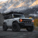 Three quarters view of a white Ford Bronco on a mountain trail, with multiple aftermarket lighting products installed, including Oculus Headlights.