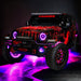 Three quarters view of a red Jeep Wrangler JL, with ColorSHIFT Oculus Headlights, and pink halo rings.