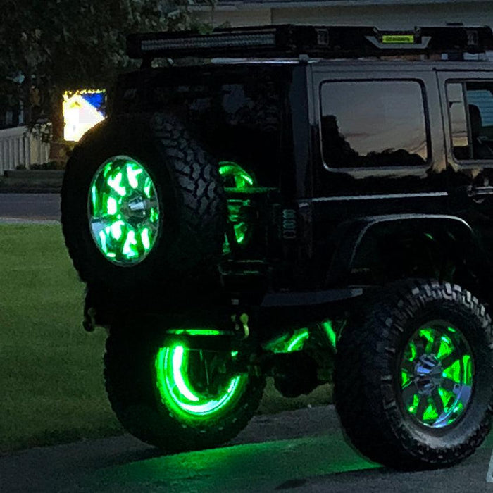 Rear three quarters view of a black Jeep with green LED Illuminated Spare Tire Wheel Ring Third Brake Light.